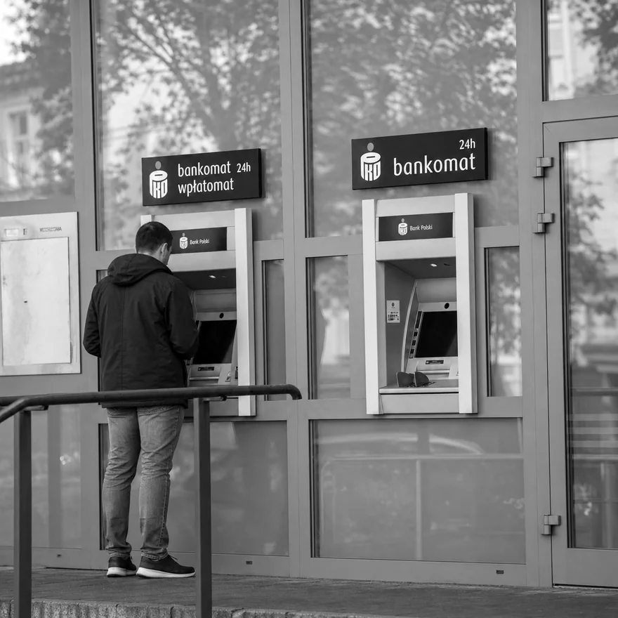 A customer using a bank cash machine on a street in Poland, banking and insurance market research in Poland